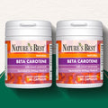 Two bottles of Nature's Best Beta Carotene capsules on a gradient background