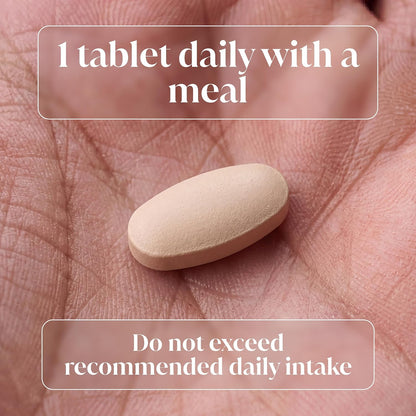 A single beige oval tablet resting on an open palm, with text overlays reading '1 tablet daily with a meal' and 'Do not exceed recommended daily intake'.