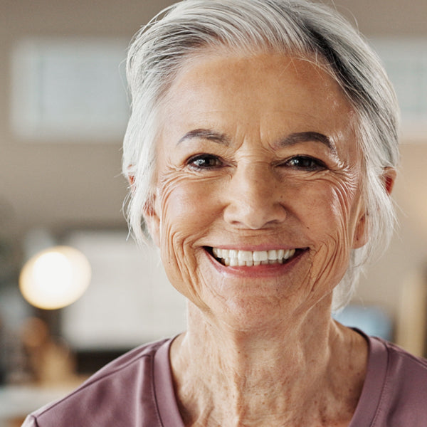 Smiling older woman with gray hair in a blurred indoor setting