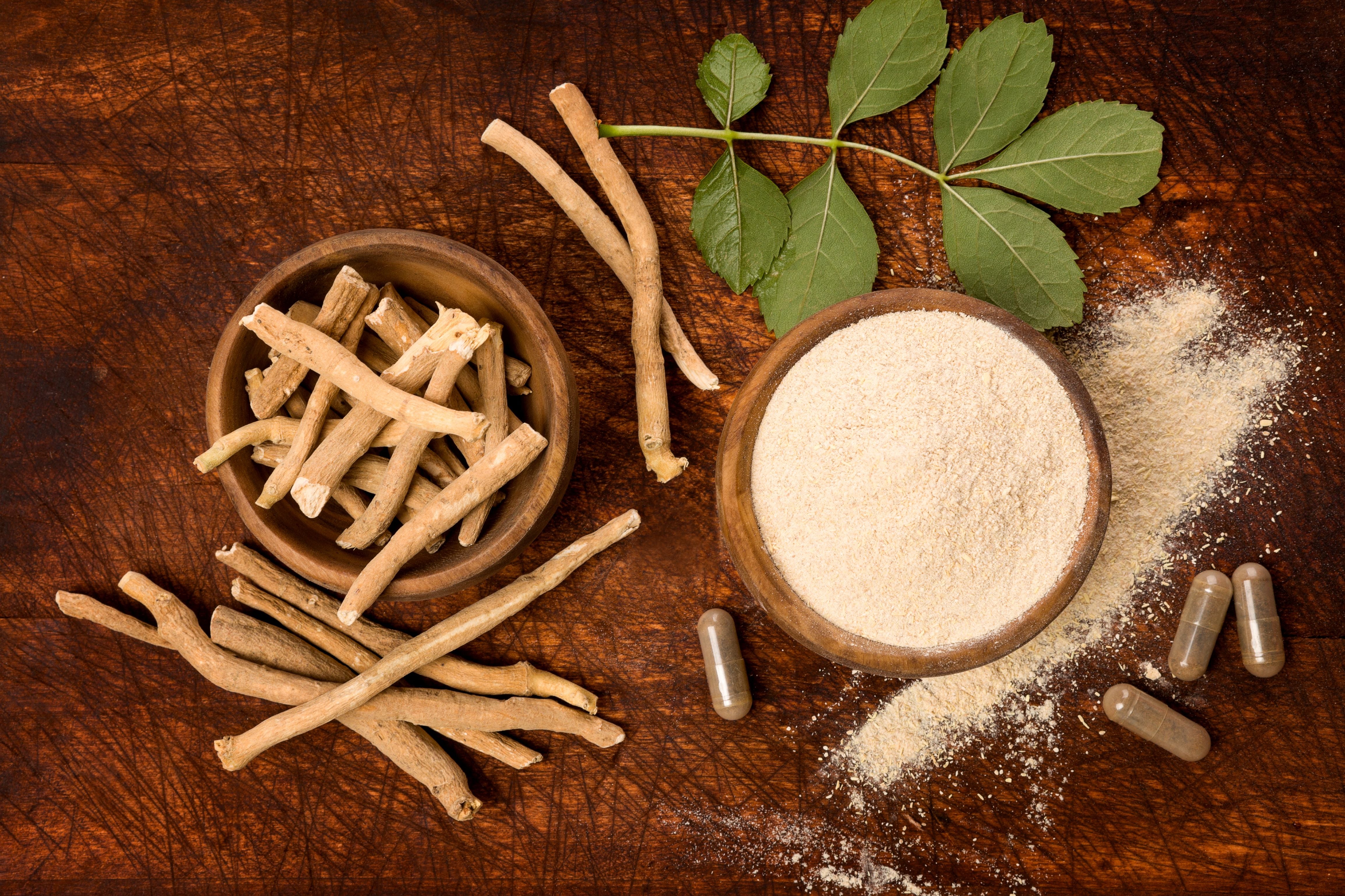 Herbal roots, powder, and capsules on a wooden surface
