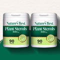 Two Plant Sterols product pots side by side on a green semicircle backgound at the bottom and a pale background at the top
