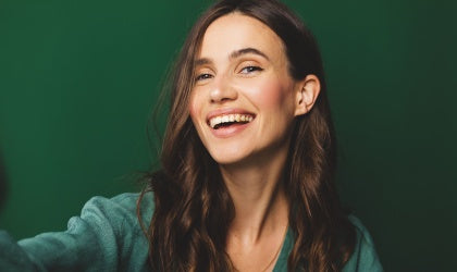 Woman with a big smile against a green background