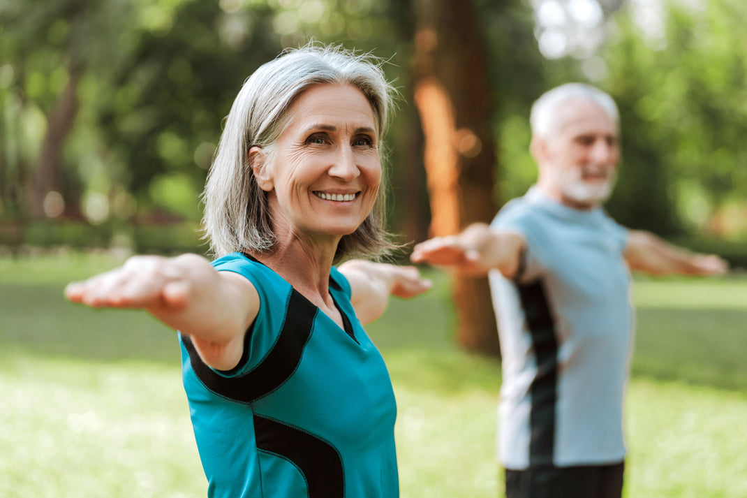 Two elderly people exercising outdoors in a park