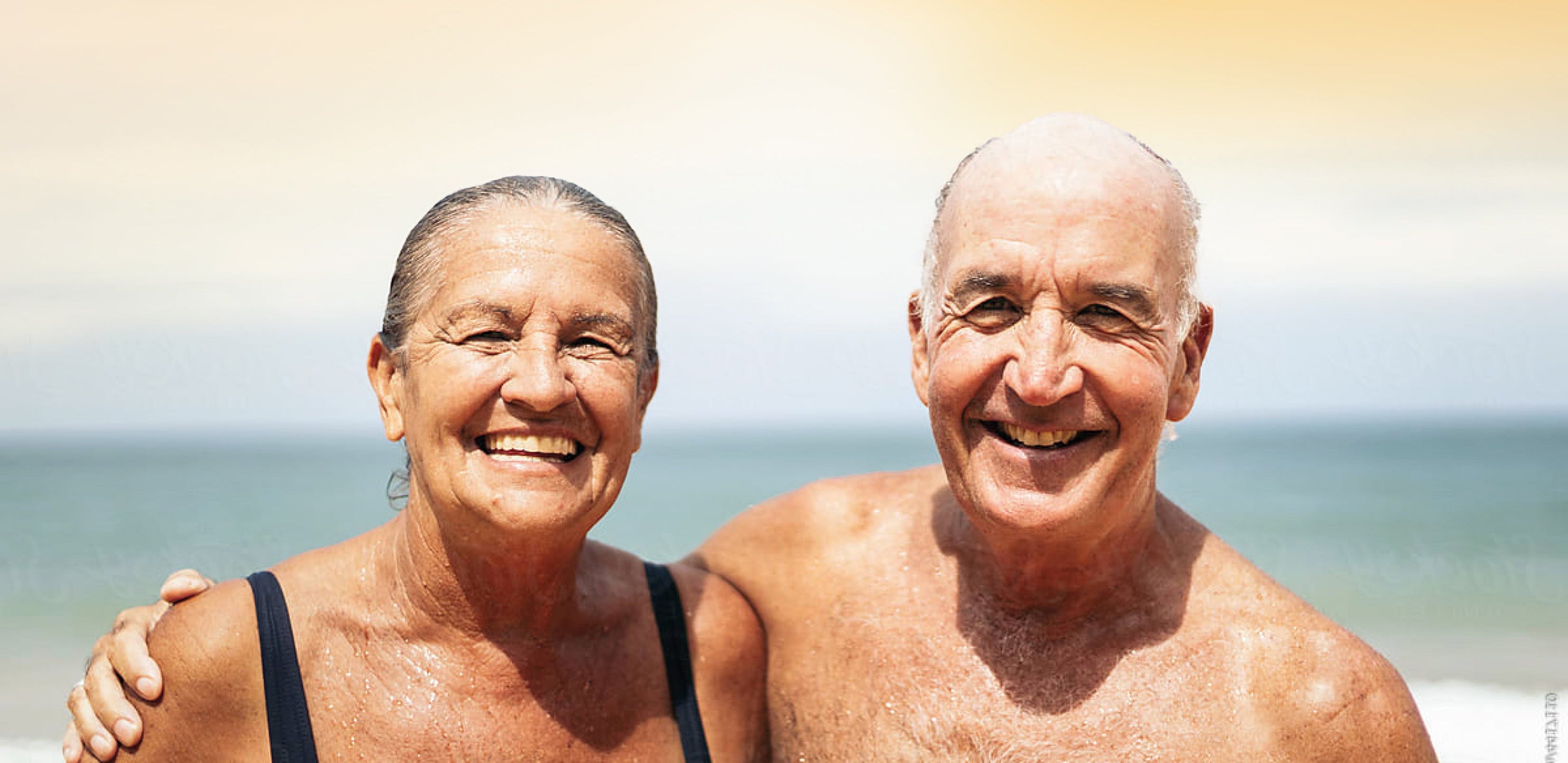 Two elderly people standing on a beach with a blurred background