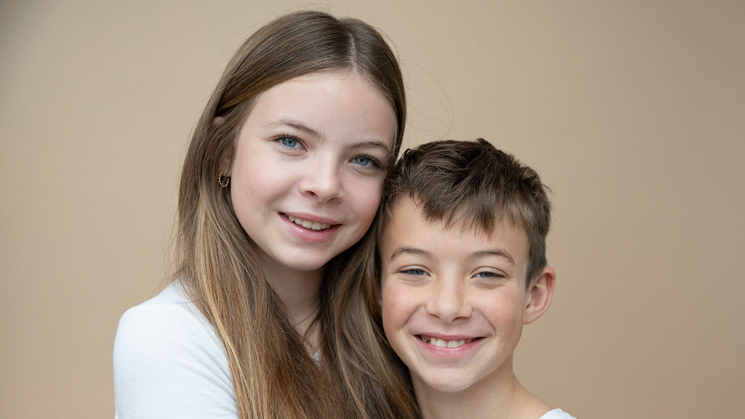 Two children smiling against a beige background