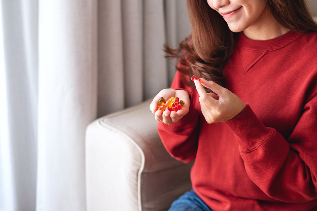 Woman in a red sweater holding colorful candies indoors.