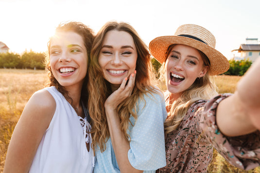 Three women taking a selfie in a field with a sunny background
