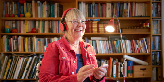 Woman wearing headphones in a room filled with bookshelves