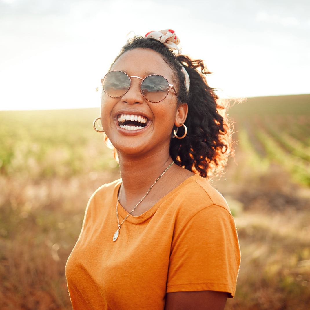 Woman wearing sunglasses and an orange shirt in a field