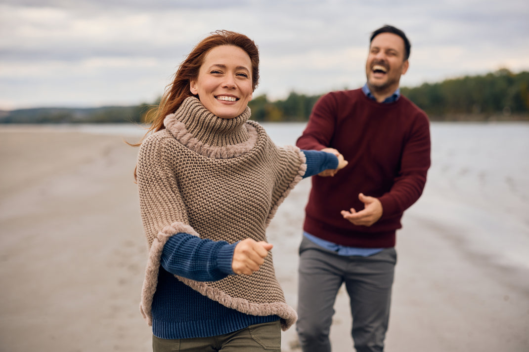 Two people walking on a sandy path with a lake in the background