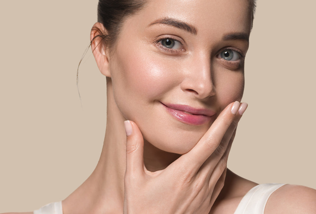 Woman touching her face with a beige background