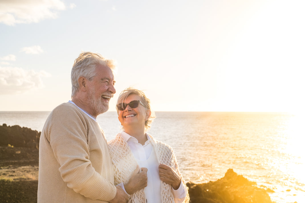 Senior couple standing on a rocky shore with a scenic background