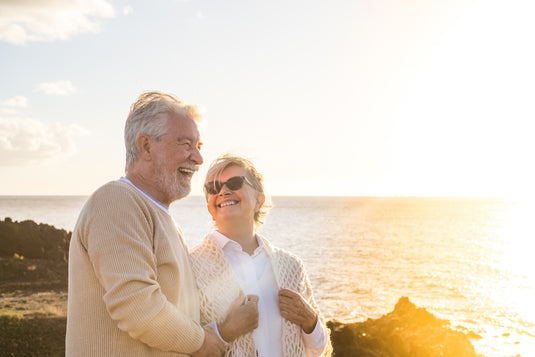 Senior couple standing on a rocky shore with a scenic background
