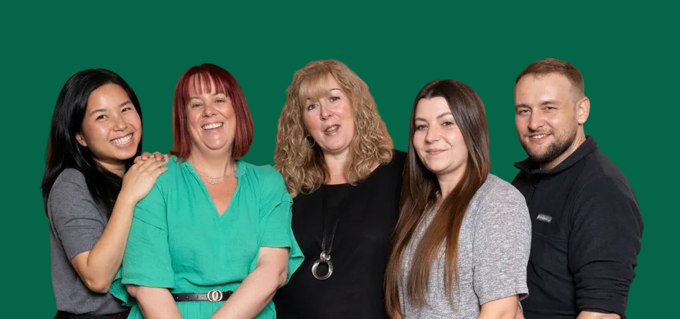 Five people posing together against a green background