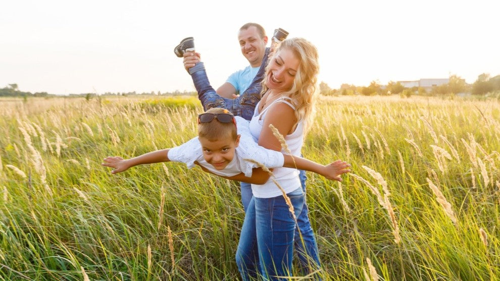 Family of three playing in a grassy field