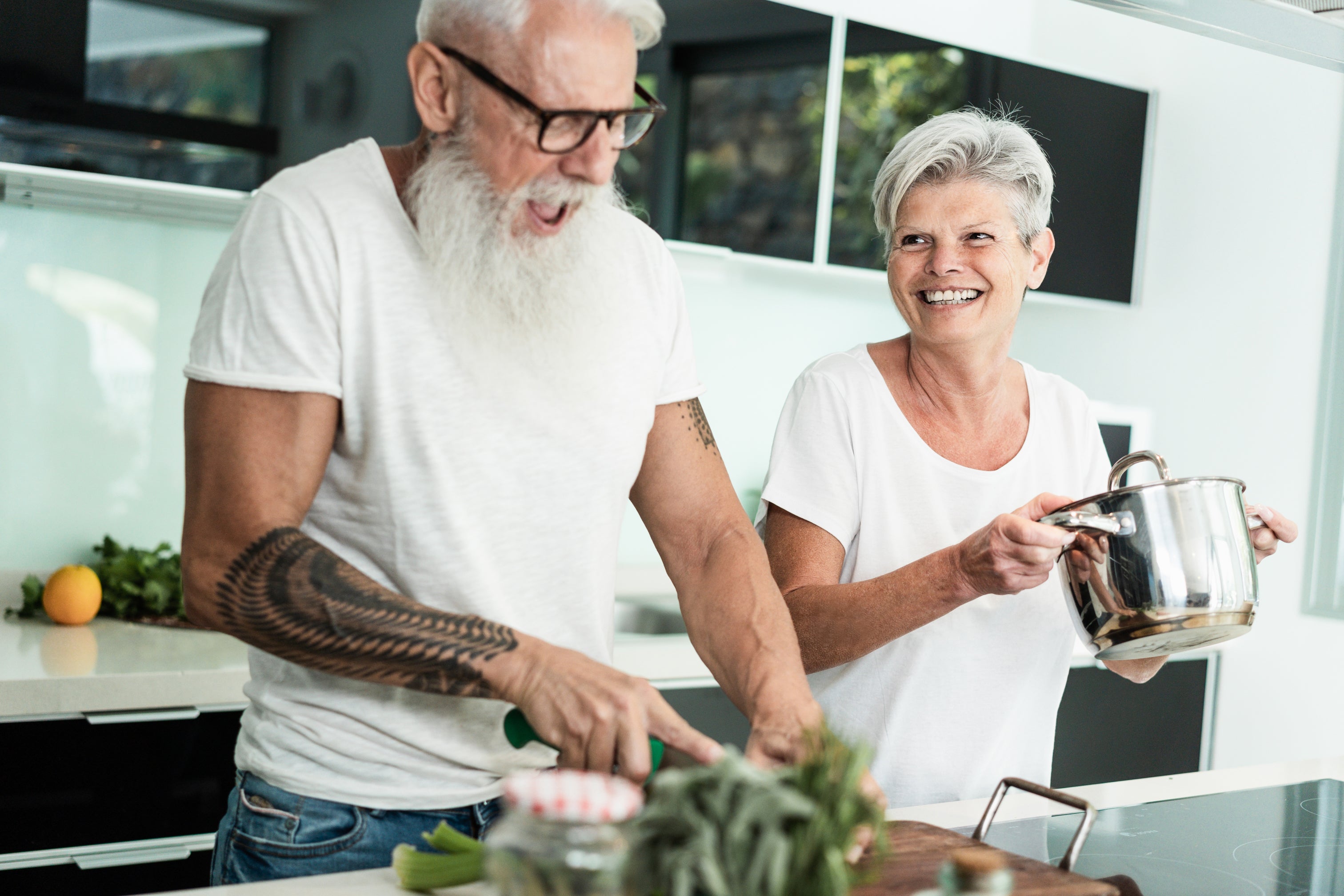 Two elderly people in a kitchen preparing food.