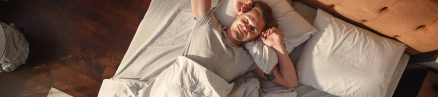 Man in bed waking up not tired